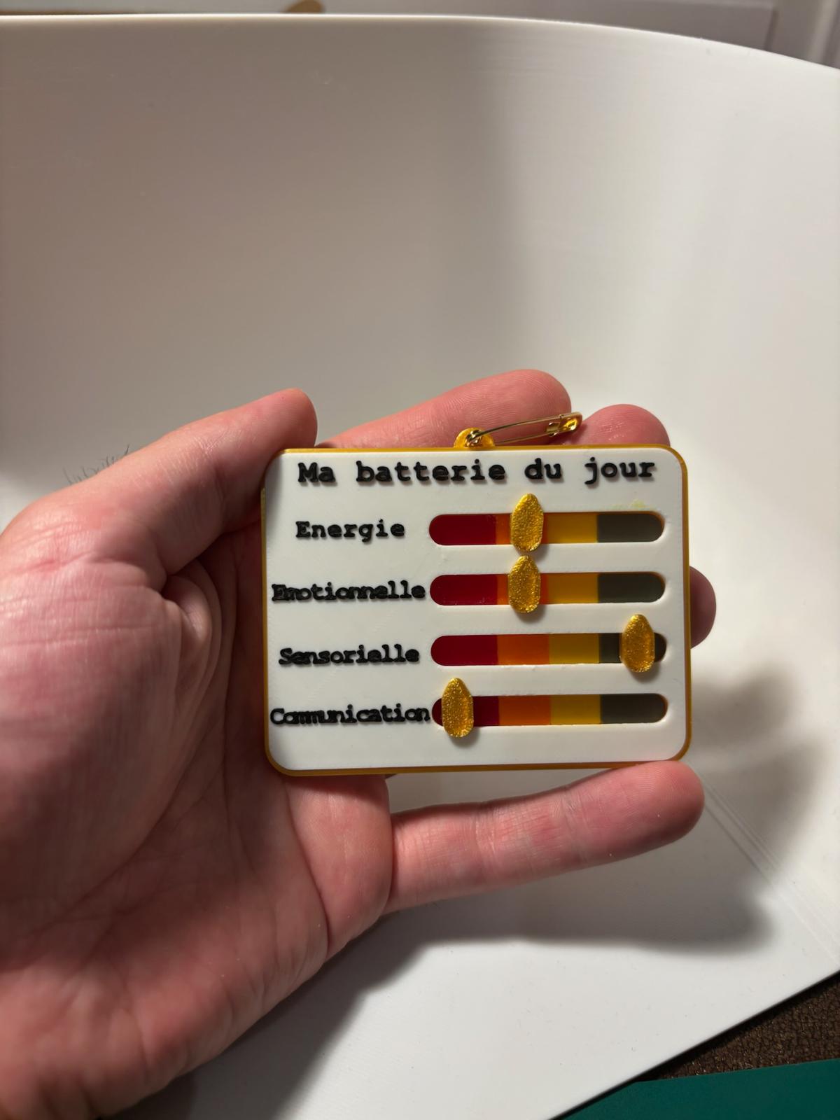 Badge « Ma batterie du jour » à curseurs tenu dans une main